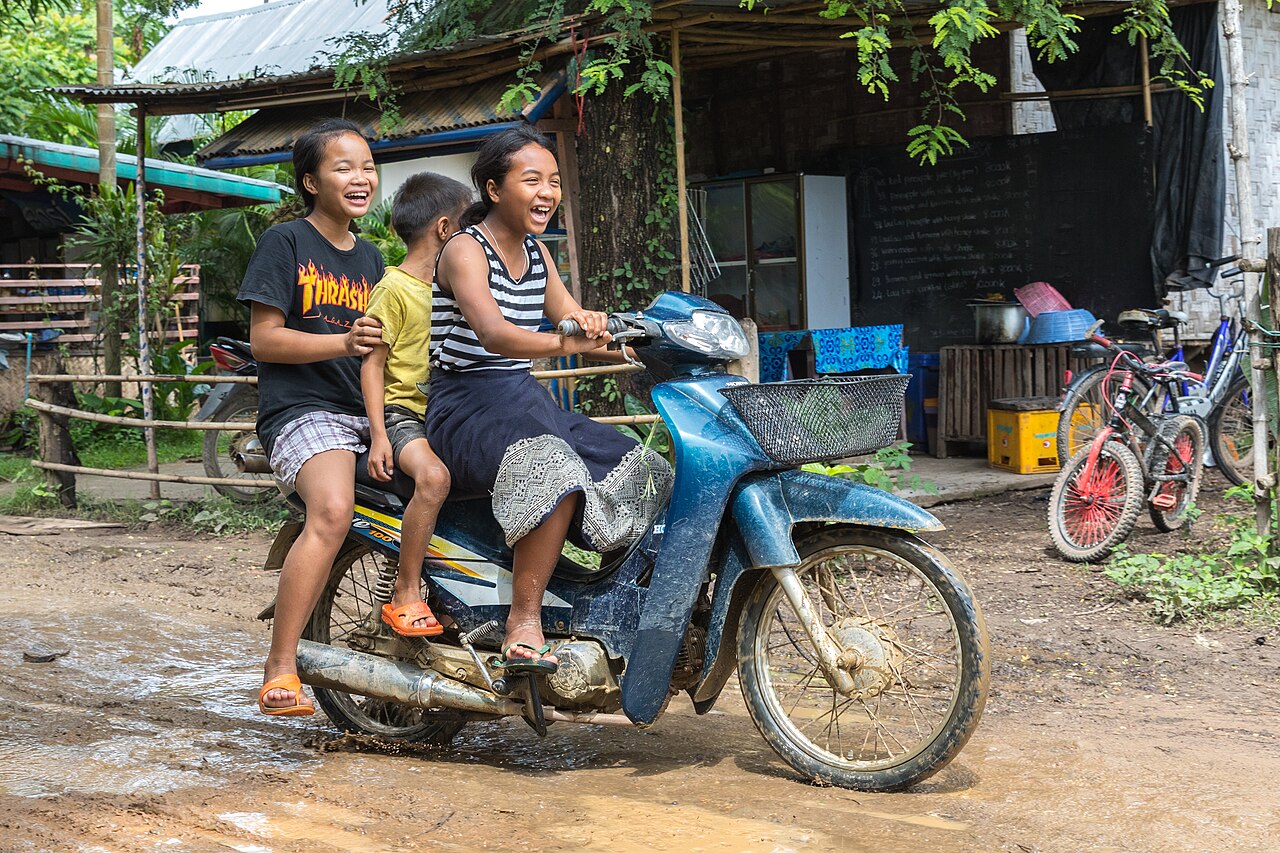 Niños riendo sobre una motocicleta en Laos